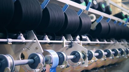 Factory mechanism is rewinding reels with threads. textile production, textile industry, textile manufacture, textile manufacturing - Powered by Adobe