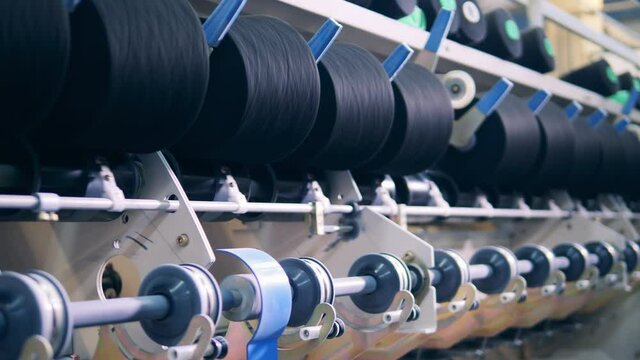 Factory mechanism is rewinding reels with threads. textile production, textile industry, textile manufacture, textile manufacturing