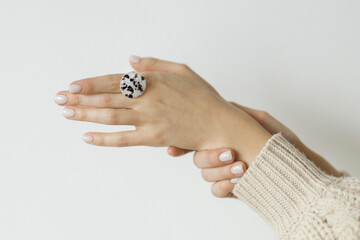 Stylish modern white and brown round ring on beautiful hand on white background. Unusual fashionable fused glass ring on female hand with white manicure. Contemporary gift