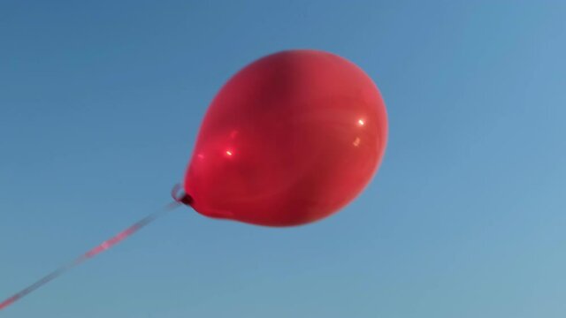 Big red hot air balloon flies against the blue sky