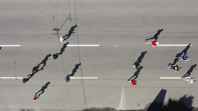 Aerial top down people running marathon, disabled persons on wheelchairs taking part, shadows of contestants on asphalt road. Healthy lifestyle and outdoor activity. Concept of sport