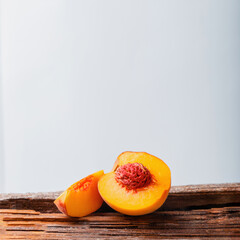 Peaches with leaves on wooden board. Peach in halves with bone. Ripe juicy peaches. Fresh organic peaches fruit on white background. Rustic minimalist style with copy space. Square