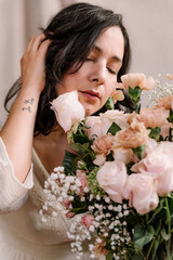 closeup portrait of young woman with flowers bouquet and natural look. close up during springtime. serious and romantic expression with eyes wide open. concept of happy spring season