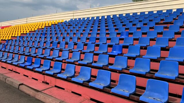 Yellow, green, red and blue seats in a row in the stadium without the player and the audience. Empty stadium or race track seats during the COVID-19 coronavirus pandemic.