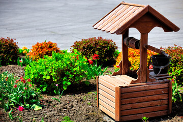 Decorative rustic wood well and flower bed. The idea for landscaping and landscaping of the territory.
