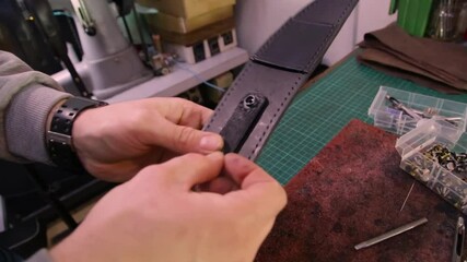The artisan nails the fastener to a leather object
