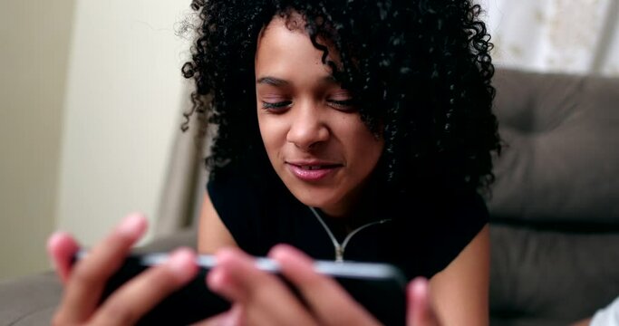 Little girl using cellphone. Hispanic black preteen child watching media on smartphone