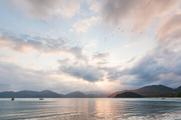 Colorful sunset view in dusk beach tropical summer climate with mountains in the background