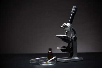 Optical microscope on a black background, petri dish and syringe for injection