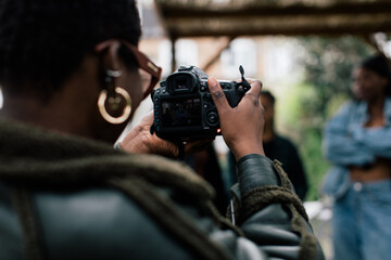 Obraz premium Close up of cool woman photographer with glasses and afro taking photographs with her camera 