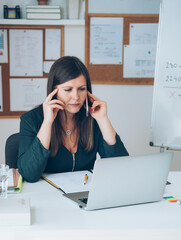 Female professor having break with online class and talking on mobile phone .
Serious teacher calling somebody on phone and preparing to working from home desk with E-learning students online.