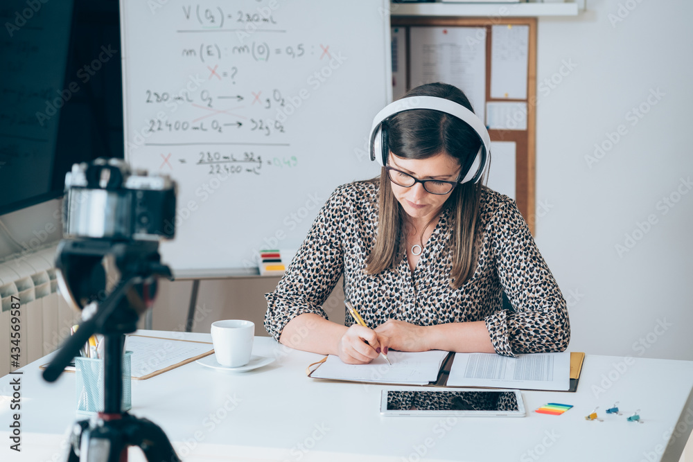 Wall mural teacher recording video tutorial for e-learning class. female professor working from home teaching o
