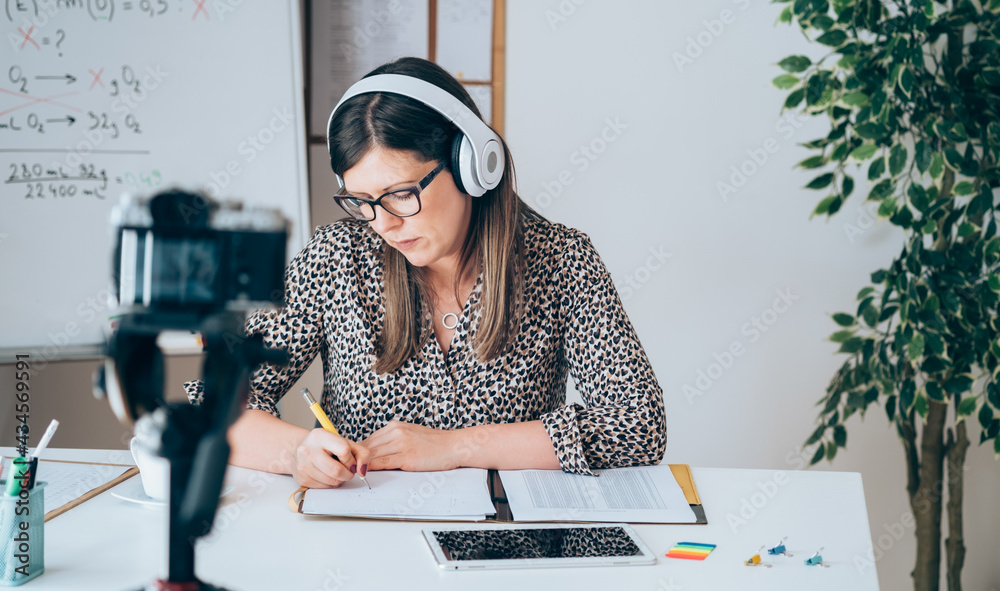 Wall mural teacher recording video tutorial for e-learning class. female professor working from home teaching o