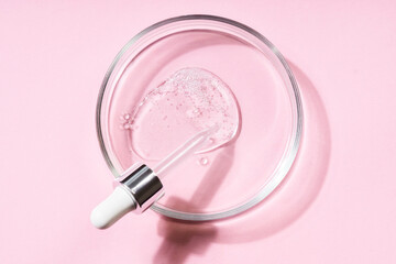 Pipette with a smear of hyaluronic acid on a round glass support, pink background. Cosmetics...