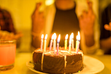 Excited arabian man ready to blow out candles on cake on birthday party with happy friends in the house