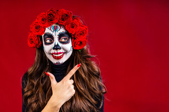nice glamorous beautiful mexican dark brown eyes woman ready to Santa Muerte day pointing at copyspace