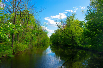 Fototapeta na wymiar Clouds and trees reflecting in the waters of the Delaware and Raritan Canal at Colonial Park. -05