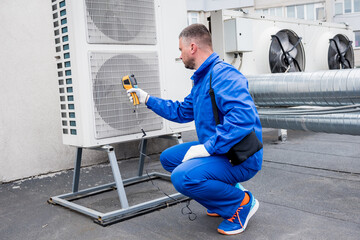 Technician uses a thermal imaging infrared thermometer to check the condensing unit heat exchanger.