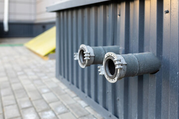 Two sockets for connecting fire hoses on the metal wall of an industrial building. Ensuring fire safety in a residential building or in commercial real estate