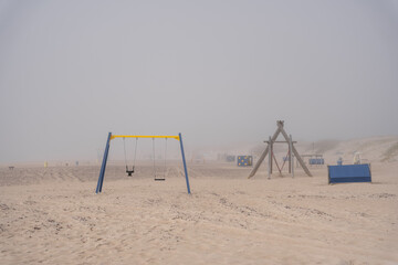Fototapeta premium The beach of the Baltic Sea in Ventspils where there are various swings and other attractions is in thick fog