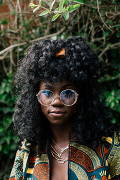 Portrait of woman with curly hair and glasses wearing African print jacket in nature
