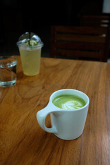 Cup of green tea latte on wooden table closeup.