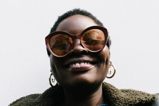 Portrait of a young woman with afro and cool sunglasses laughing 