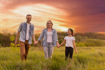 Happy family in the park evening light. The lights of a sun. Mom, dad and baby happy walk at sunset. The concept of a happy family