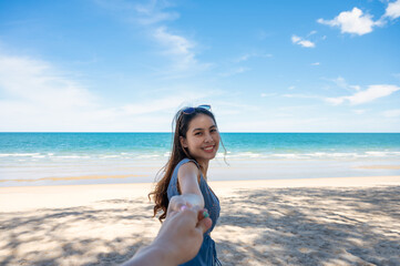Fototapeta na wymiar Beautiful young asian woman holding hands with boyfriend on the beach in tropical sea at vacation