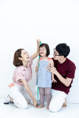 Fototapeta premium Father and mother, children, girls, disabilities, and cerebral development down syndrome are measuring daughter's waist circumference with a tape measure in the living room in the home.