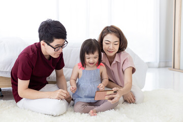 Girls with Down Syndrome cerebral learning disability, laughing, playing, parents in white bedrooms, teaching their children to watch educational materials using a smartphone. Happy education concept