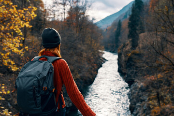 woman tourist with backpack admires nature river mountains travel