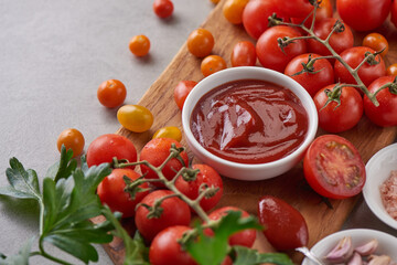 tomato sauce with garlic and  vibrant green leaves of the italian parsley plant. tomato ketchup sauce in a bowl with spices, herbs and cherry tomatoes. top view.
