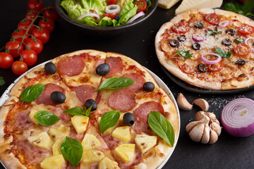 assorted foodset on table. Italian pizza and pizza cooking ingredients on dark stone background. tomatoes on vine, mozzarella, black olives, herbs and spices, vegetable salad. top view.