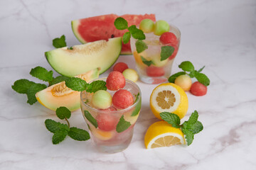 Refreshing summer citrus cocktail with lemon, watermelon and melon with mint and ice cubes in glass, homemade fresh fruit, fruit drink for healthy concept, selective focus.