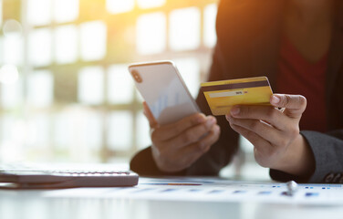 Close up woman hand using credit card and smartphone laptop for buying online shopping