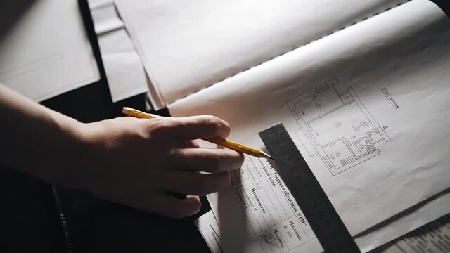 The guy makes a drawing using a pencil and ruler. He's a devil late at night