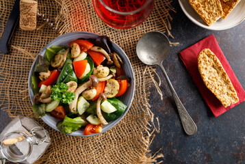 mushroom salad in a bowl. Summer meal a salad with himeji, oyster fungus, white Paris mushrooms mixed with young lettuce, tomatoes and cucumber.