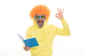 Happy man in funky wig show OK sign gesture reading school book in geek sunglasses, education