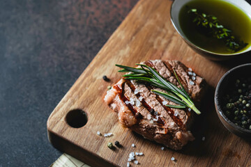 Grilled beef steak with with rosemary, spices and salt on cutting board. Selective focus