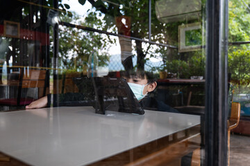 Asian boy watching computer tablet with a medical face mask.