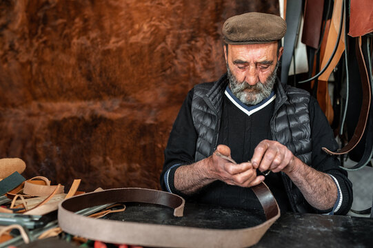 Senior bearded working with genuine leather making a strap. - Powered by Adobe