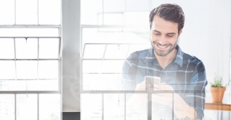 Composition of smiling man using smartphone in office with white overlay