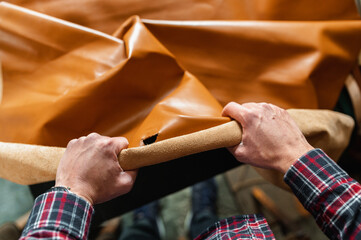 Point of view of man unrolling a piece of brown genuine leather.