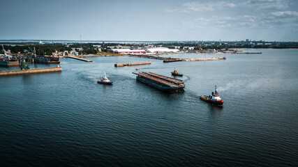 Aerial drone footage of industrial shipyard complex and ships towing cargo in the sea. 
