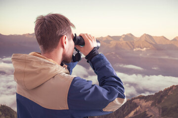 young person hiking in the mountains and using binoculars, travel concept