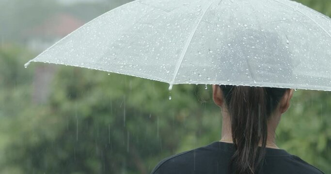 Woman is holding umbrella standing under the rain