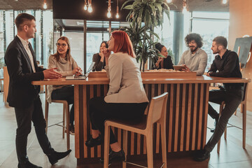 Group of friends hanging out in a coffee shop with a laptop amongst them. Happy young people sitting at restaurant using laptop