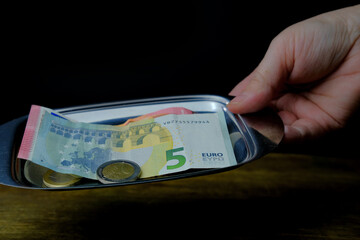 close-up of a metal tray for money in a female hand, euro banknotes and coins, Restaurant bill,...