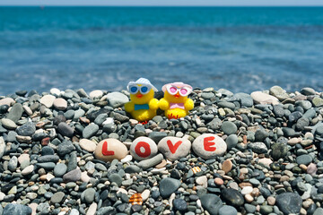 Fototapeta na wymiar Two toy chicks in love on sea beach 